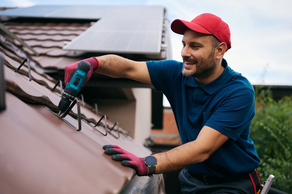 Smiling roofer carrying out maintenance on a tiled house roof